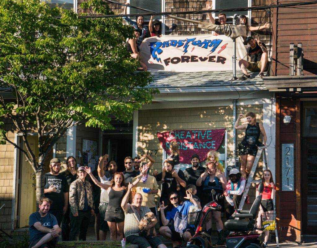 RadStorm members in front of the space, with two banners which read "RadStorm Forever" and "Creative Resistance." 