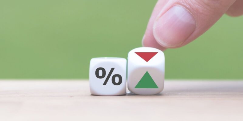A hand rolls two dice—one percent, one with red down and green up arrows—reflecting community bonds.