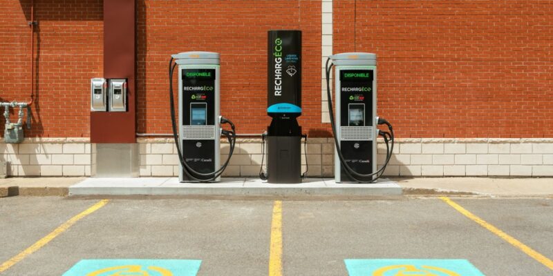 Deux bornes de recharge pour véhicules électriques, installées devant un mur de briques et à proximité de places de stationnement, favorisent les liens entre les habitants.